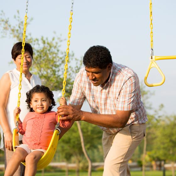 parents with kid on swing