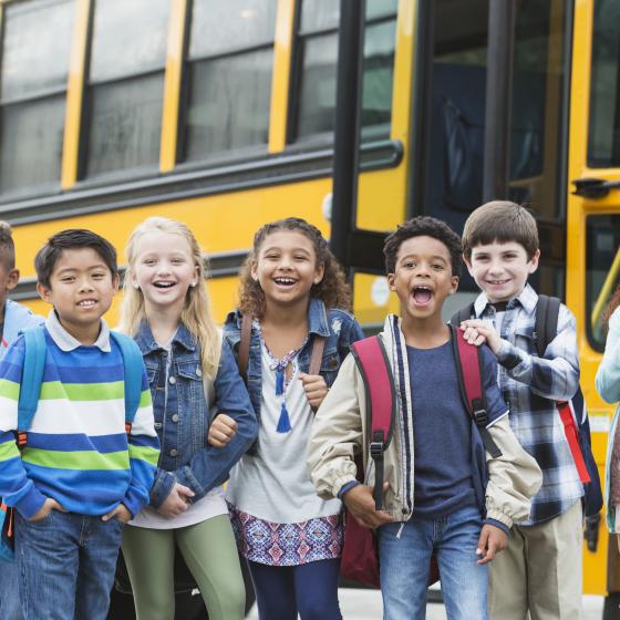 multi-racial students in front of school bus