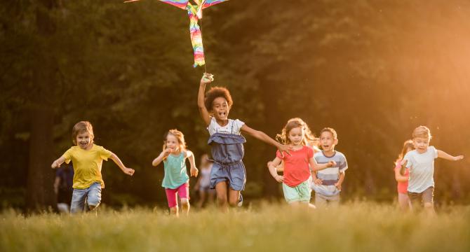 multi-racial kids running in grassy field